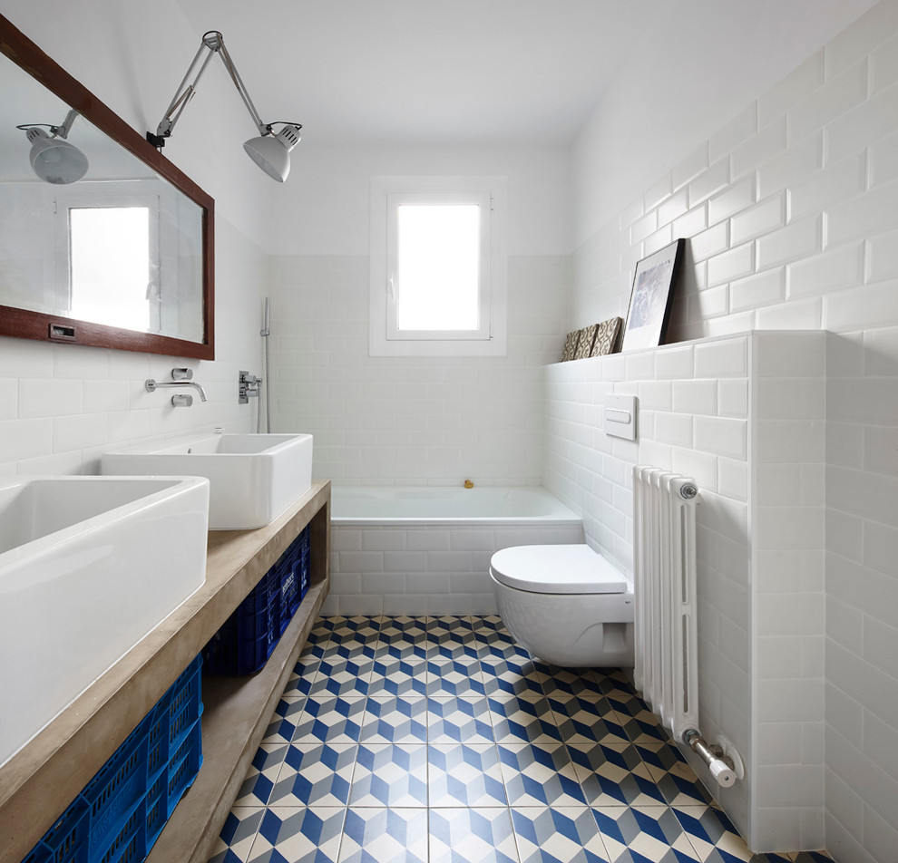 This is an example of a mid-sized eclectic bathroom in Barcelona with an alcove tub, a one-piece toilet, white tile, subway tile, white walls, ceramic floors, a vessel sink and concrete benchtops.