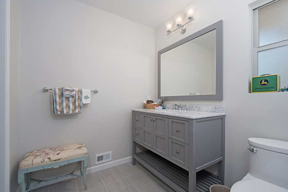 Design ideas for a small beach style 3/4 bathroom in San Diego with recessed-panel cabinets, grey cabinets, an alcove tub, an alcove shower, a two-piece toilet, gray tile, porcelain tile, grey walls, porcelain floors, an undermount sink, quartzite benchtops, grey floor and a shower curtain.