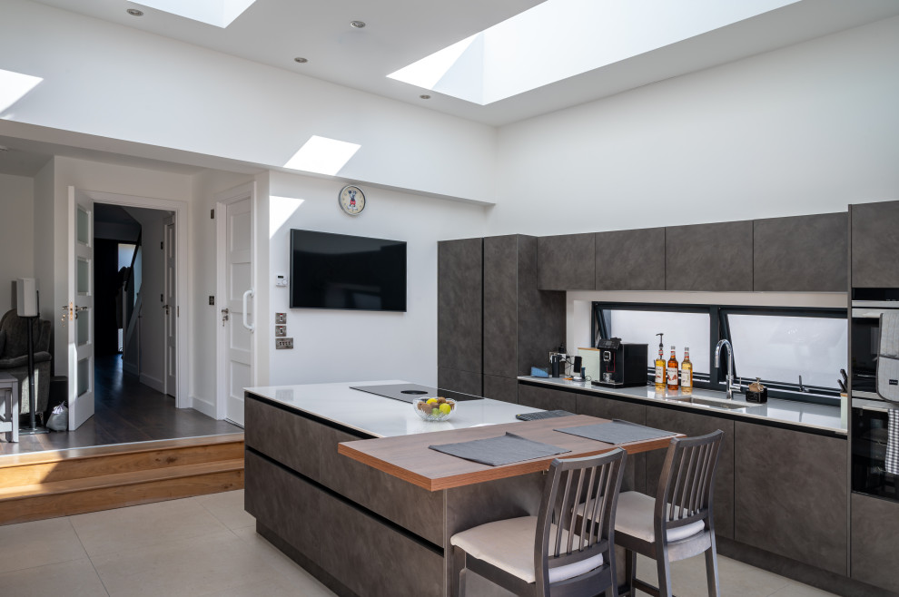 This is an example of a Small Galley kitchen/diner in Dublin with an Integrated Sink, Flat-panel Cabinets, Window Splashback, Ceramic Flooring and a Vaulted Ceiling.