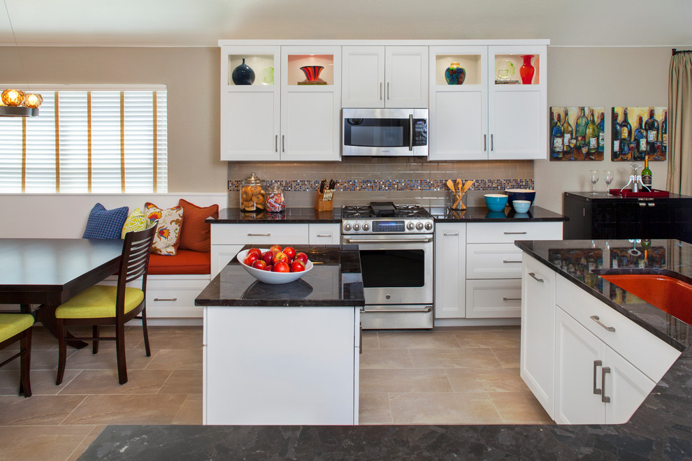 This is an example of a large transitional galley eat-in kitchen in Austin with an undermount sink, shaker cabinets, white cabinets, granite benchtops, grey splashback, glass tile splashback, stainless steel appliances, porcelain floors and multiple islands.