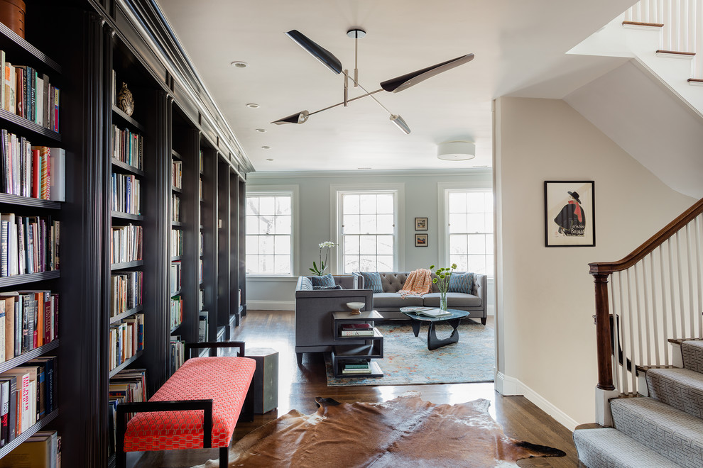 Design ideas for an expansive transitional open concept living room in Boston with white walls, dark hardwood floors, a standard fireplace, brown floor and a library.