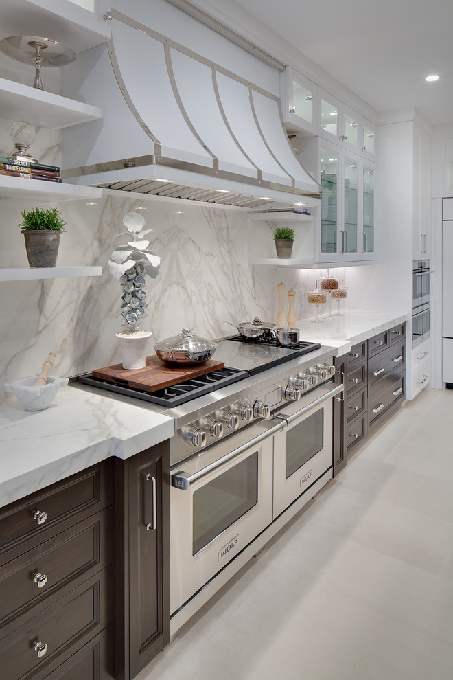 This is an example of a large transitional l-shaped open plan kitchen in Orange County with an undermount sink, shaker cabinets, white cabinets, quartz benchtops, white splashback, stone slab splashback, panelled appliances, limestone floors and with island.