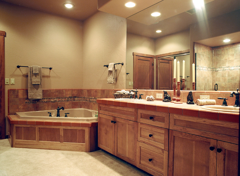 Example of a large transitional master multicolored tile and ceramic tile ceramic tile corner bathtub design with a drop-in sink, recessed-panel cabinets, medium tone wood cabinets, tile countertops and beige walls