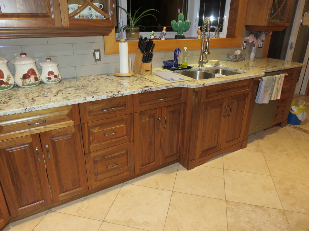 Open concept kitchen - large transitional l-shaped ceramic tile open concept kitchen idea with raised-panel cabinets, medium tone wood cabinets, granite countertops, stainless steel appliances, an island, a double-bowl sink, white backsplash and subway tile backsplash