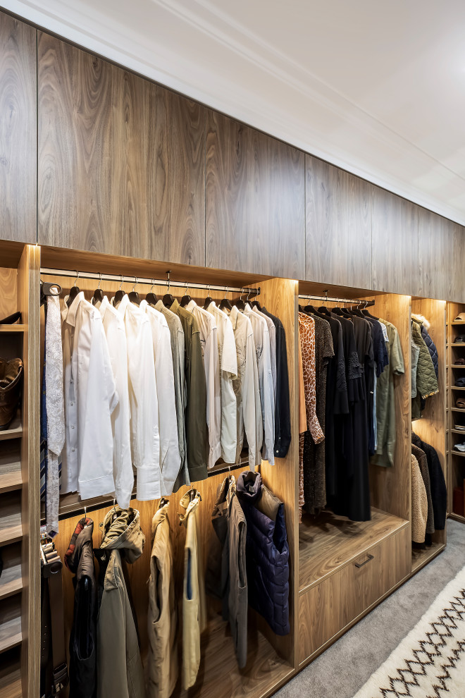 Inspiration for a large modern gender-neutral walk-in wardrobe in Sydney with flat-panel cabinets, medium wood cabinets, carpet and beige floor.