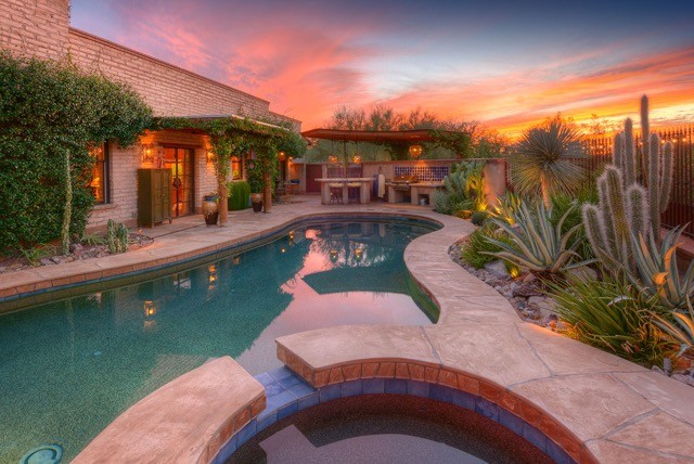 Design ideas for a mid-sized backyard custom-shaped pool in Phoenix with a hot tub and natural stone pavers.