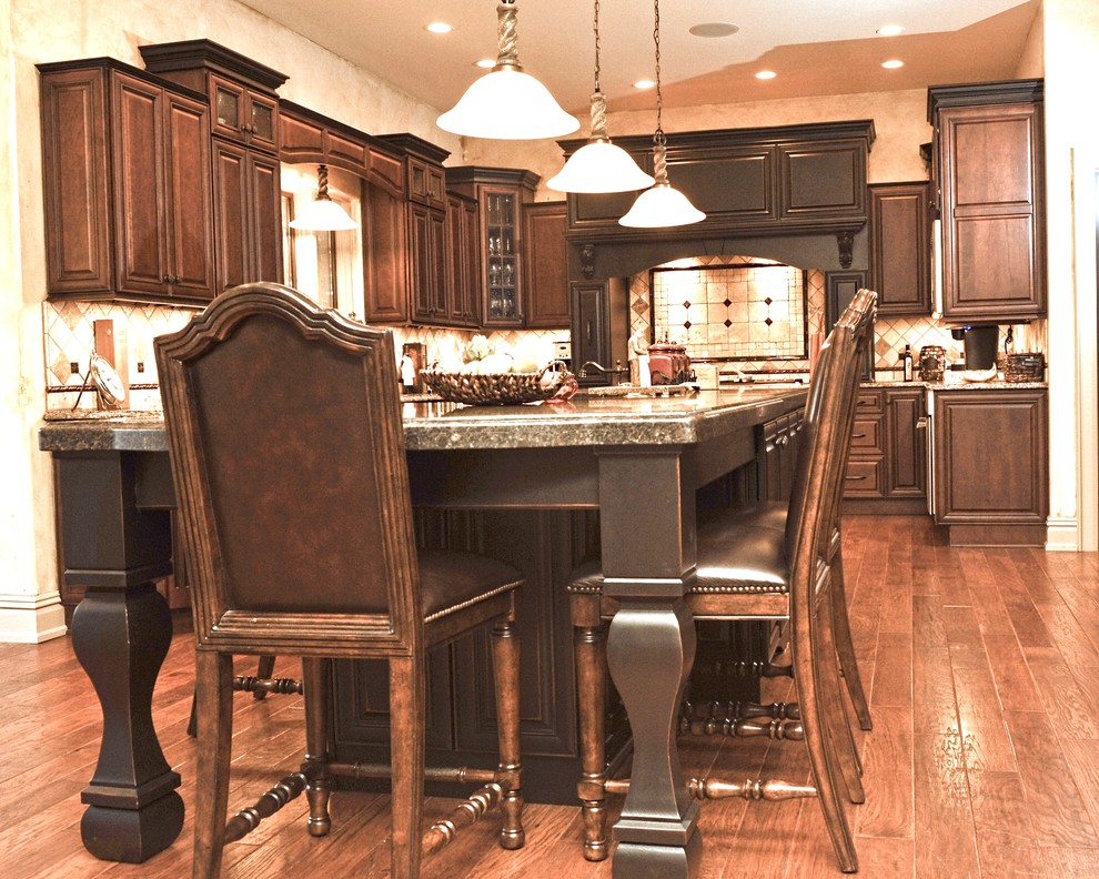 Example of a large transitional u-shaped dark wood floor eat-in kitchen design with an undermount sink, raised-panel cabinets, dark wood cabinets, granite countertops, beige backsplash, ceramic backsplash, stainless steel appliances and an island