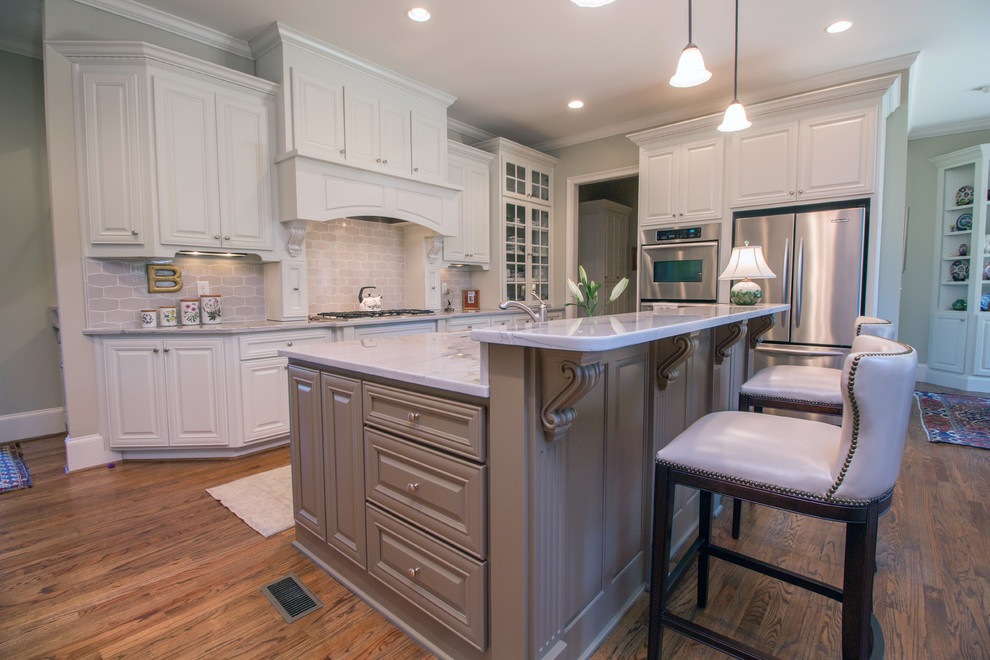 Inspiration for a mid-sized traditional l-shaped eat-in kitchen in Atlanta with an undermount sink, raised-panel cabinets, white cabinets, quartzite benchtops, grey splashback, stone tile splashback, stainless steel appliances, medium hardwood floors and with island.