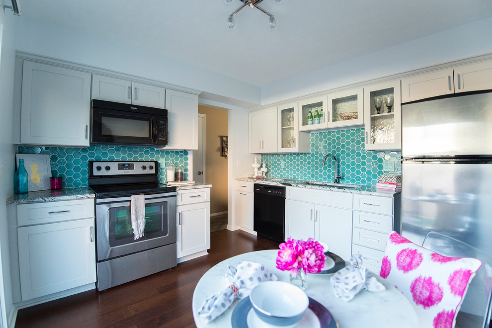 This is an example of a small eclectic l-shaped separate kitchen in Omaha with an undermount sink, shaker cabinets, grey cabinets, granite benchtops, blue splashback, glass tile splashback, stainless steel appliances, dark hardwood floors and no island.