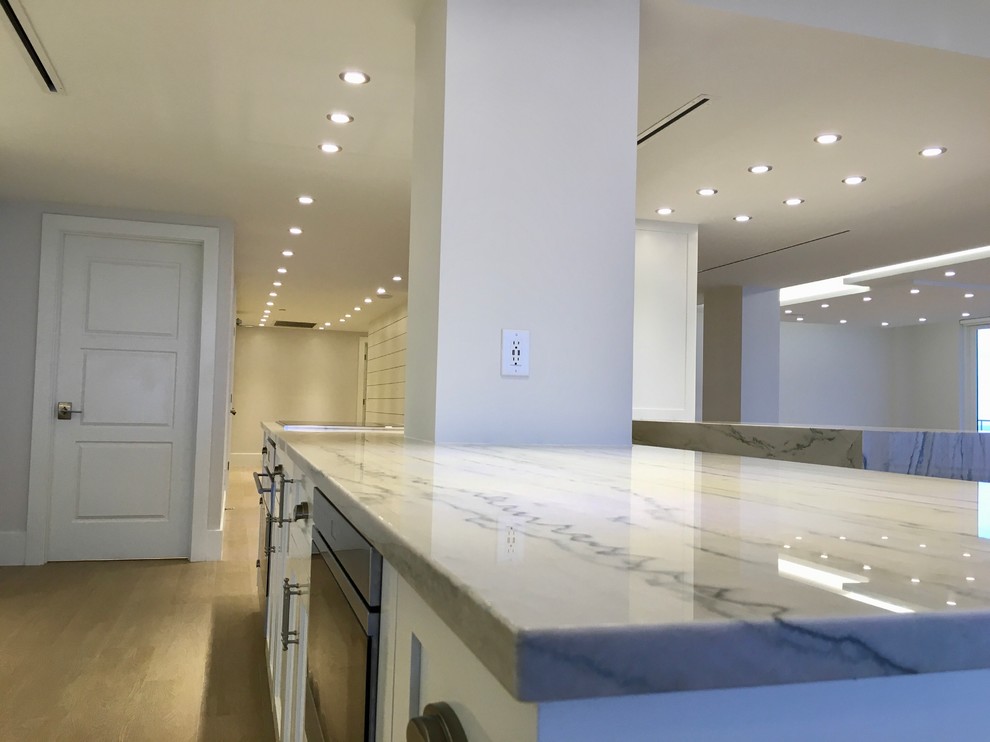 Large transitional galley light wood floor and beige floor open concept kitchen photo in Miami with an undermount sink, shaker cabinets, white cabinets, marble countertops, gray backsplash, marble backsplash, stainless steel appliances and an island