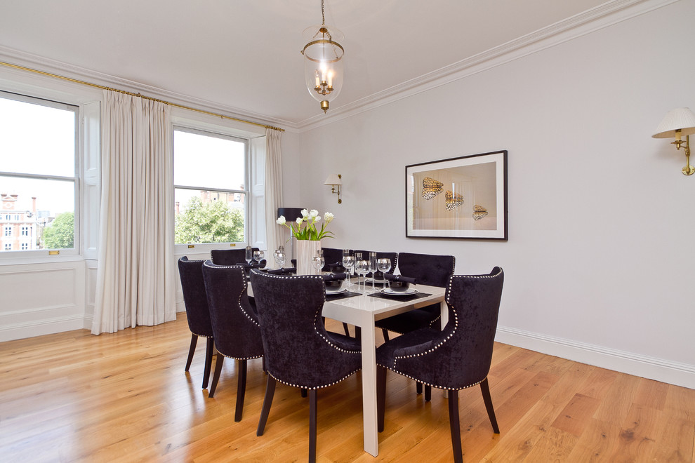 Photo of a contemporary dining room in London with white walls and medium hardwood floors.