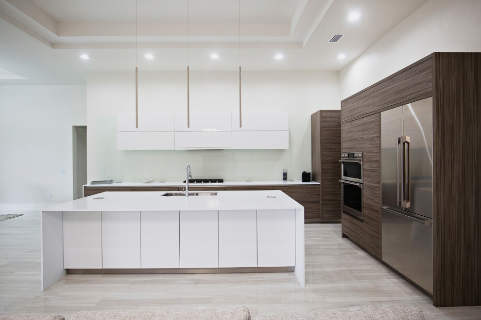 Photo of a large modern l-shaped eat-in kitchen in Miami with a drop-in sink, flat-panel cabinets, medium wood cabinets, quartzite benchtops, glass sheet splashback, stainless steel appliances, ceramic floors, with island, beige floor and recessed.