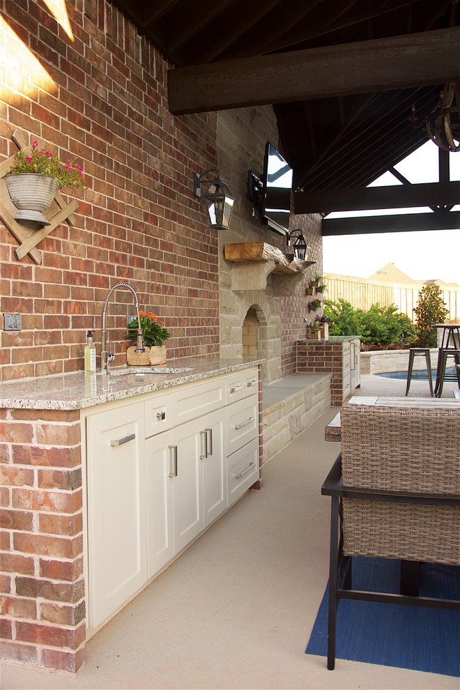 This is an example of a large country backyard patio in Austin with an outdoor kitchen, concrete slab and a pergola.