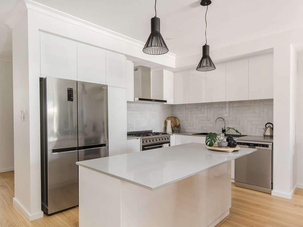 Inspiration for a mid-sized contemporary l-shaped kitchen in Perth with white cabinets, quartz benchtops, grey splashback, stainless steel appliances, laminate floors, with island, grey benchtop, flat-panel cabinets, a drop-in sink and beige floor.