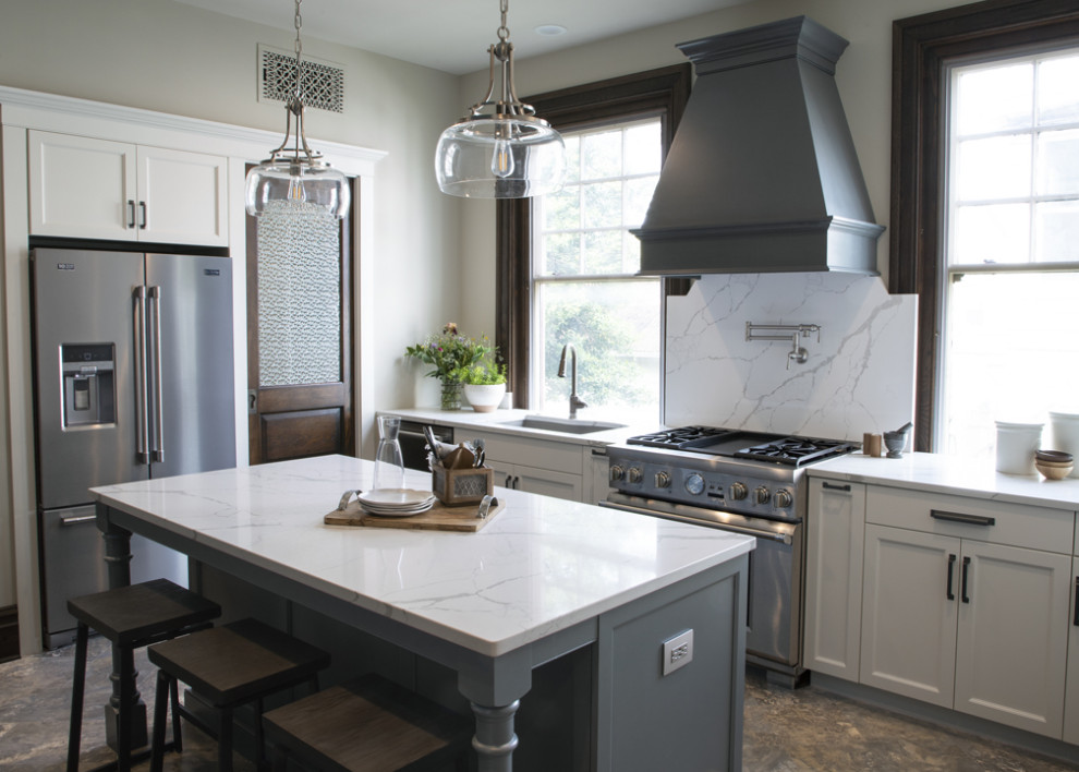Inspiration for a transitional l-shaped kitchen remodel with an undermount sink, white backsplash, stone slab backsplash, stainless steel appliances, an island and white countertops