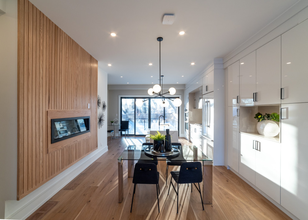 This is an example of a medium sized retro kitchen/dining room in Toronto with beige walls, light hardwood flooring, a hanging fireplace and beige floors.