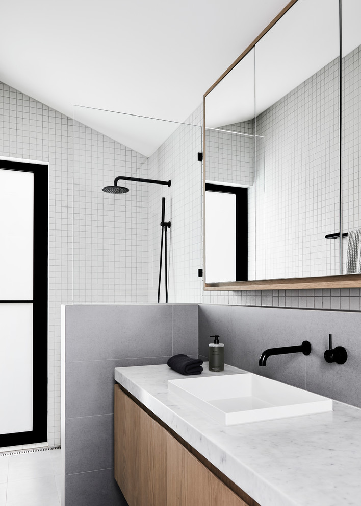 This is an example of a small contemporary master bathroom in Melbourne with furniture-like cabinets, light wood cabinets, an open shower, a wall-mount toilet, gray tile, ceramic tile, white walls, ceramic floors, a drop-in sink, marble benchtops, grey floor, an open shower and white benchtops.