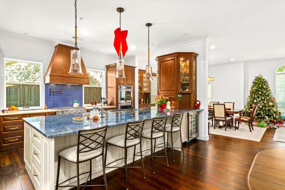 This is an example of a large classic galley open plan kitchen in Houston with a submerged sink, raised-panel cabinets, medium wood cabinets, granite worktops, blue splashback, terracotta splashback, stainless steel appliances, medium hardwood flooring, a breakfast bar, brown floors and blue worktops.
