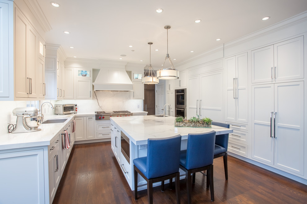 Kitchen - transitional medium tone wood floor and orange floor kitchen idea in New York with an undermount sink, shaker cabinets, white cabinets, white backsplash, stainless steel appliances and an island