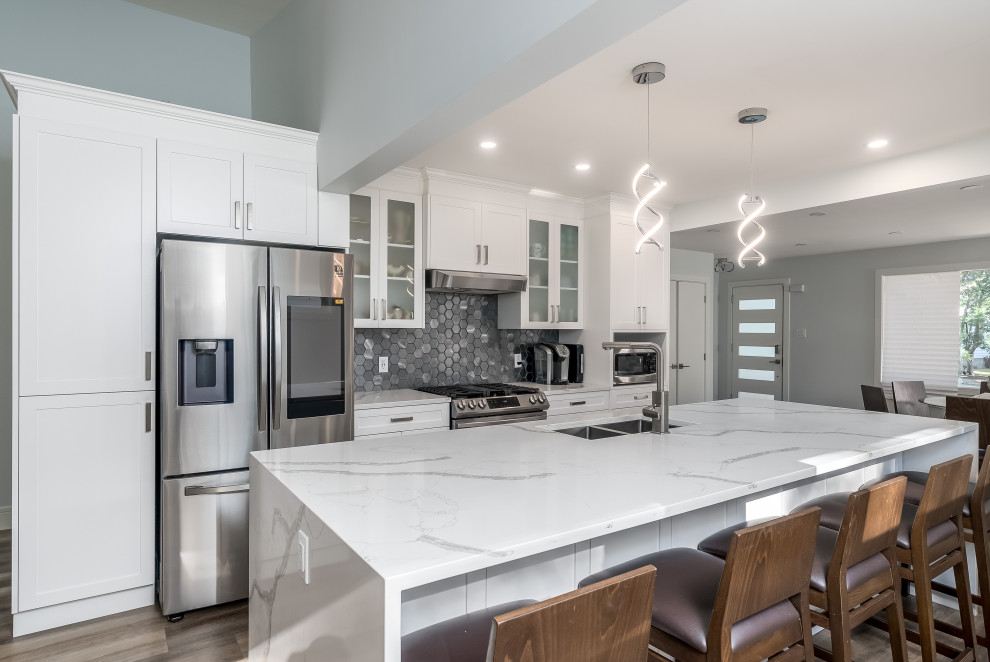 Transitional kitchen photo in Edmonton with shaker cabinets, white cabinets, quartzite countertops, gray backsplash, cement tile backsplash, stainless steel appliances, an island and white countertops