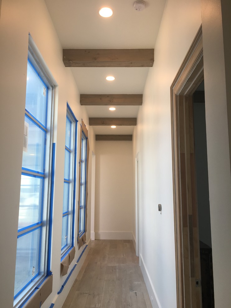 This is an example of a mid-sized transitional hallway in New Orleans with white walls, medium hardwood floors and brown floor.