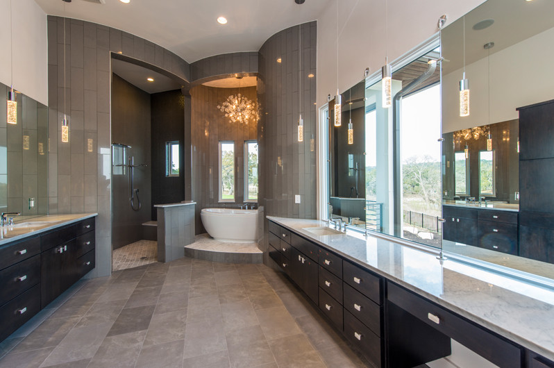 Inspiration for a large contemporary master gray tile freestanding bathtub remodel in Austin with dark wood cabinets and solid surface countertops
