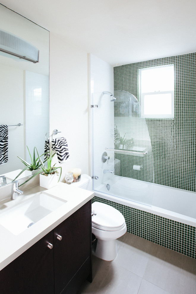 Design ideas for a contemporary bathroom in San Francisco with an undermount sink, flat-panel cabinets, dark wood cabinets, an alcove tub, a shower/bathtub combo, a two-piece toilet, green tile, glass tile, white walls and ceramic floors.