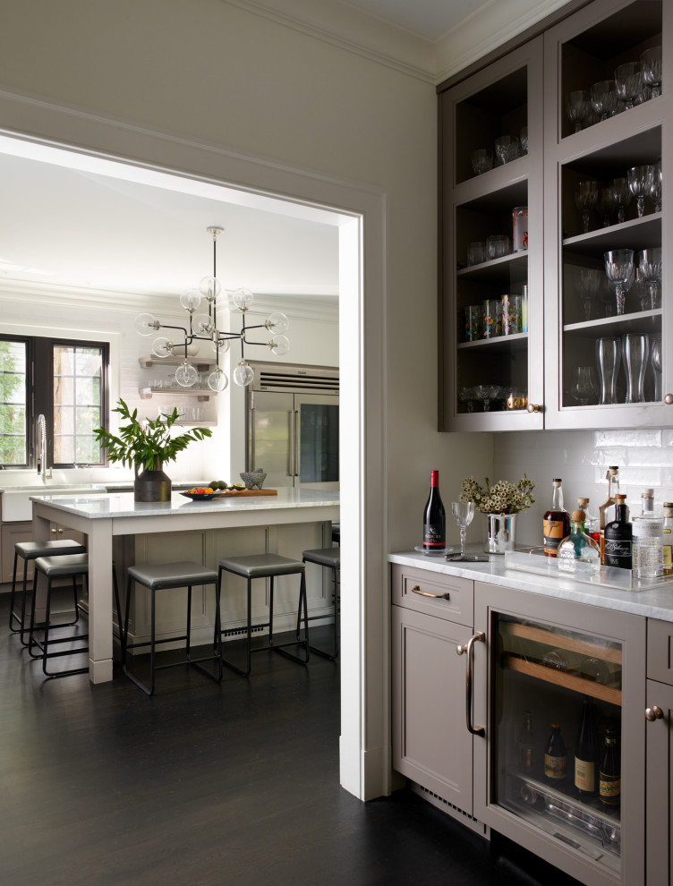 This is an example of a small classic single-wall wet bar in Boston with a built-in sink, recessed-panel cabinets, grey cabinets, marble worktops, white splashback, metro tiled splashback, dark hardwood flooring, black floors and white worktops.
