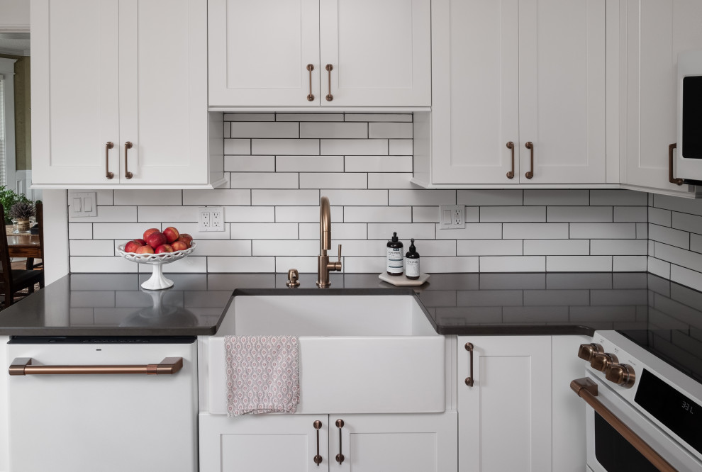 Small traditional u-shaped separate kitchen in Other with an undermount sink, flat-panel cabinets, white cabinets, quartz benchtops, white splashback, subway tile splashback, white appliances, medium hardwood floors, with island, brown floor and white benchtop.