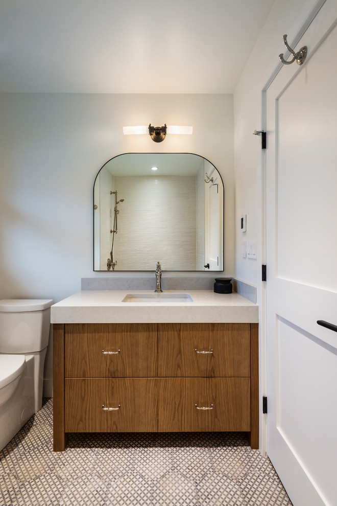 Bathroom - mid-sized rustic 3/4 porcelain tile and gray floor bathroom idea in Vancouver with flat-panel cabinets, medium tone wood cabinets, a two-piece toilet, white walls, an undermount sink, quartz countertops and beige countertops