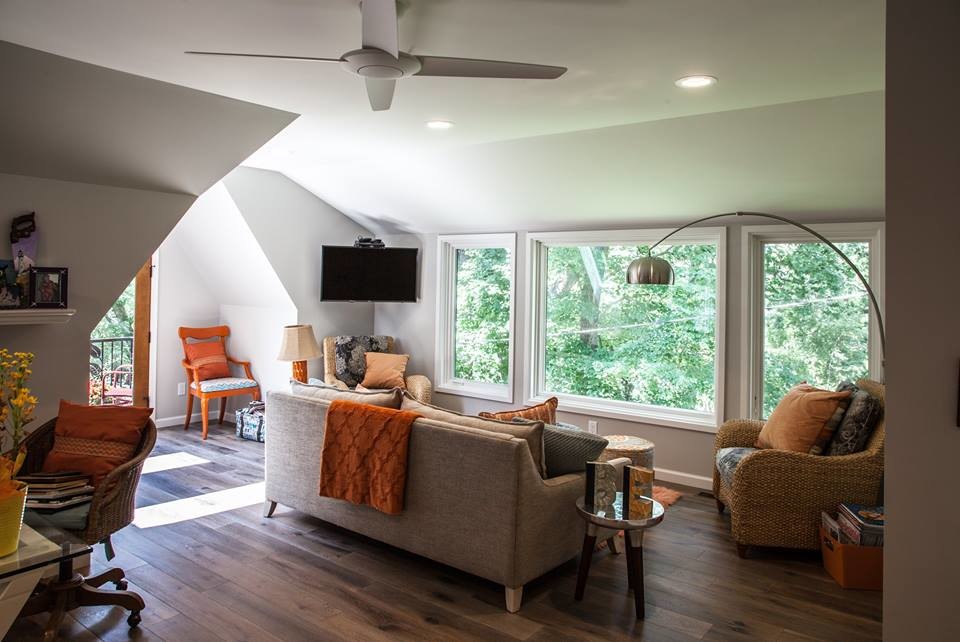 This is an example of a mid-sized contemporary enclosed family room in Other with grey walls, dark hardwood floors, no fireplace, a corner tv and brown floor.