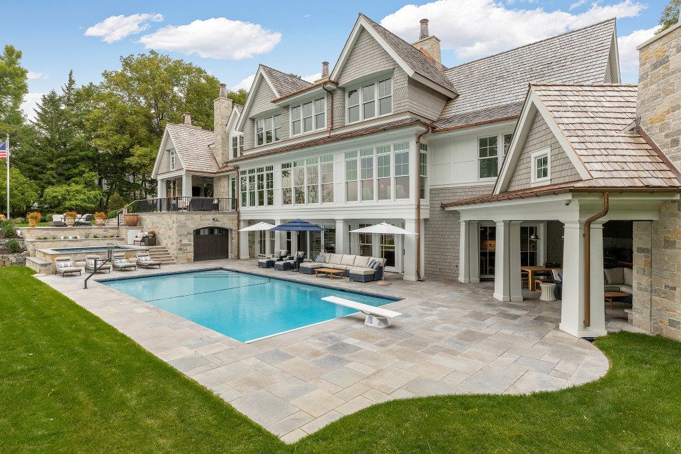 На фото: большой прямоугольный бассейн на заднем дворе в морском стиле с домиком у бассейна и покрытием из каменной брусчатки с