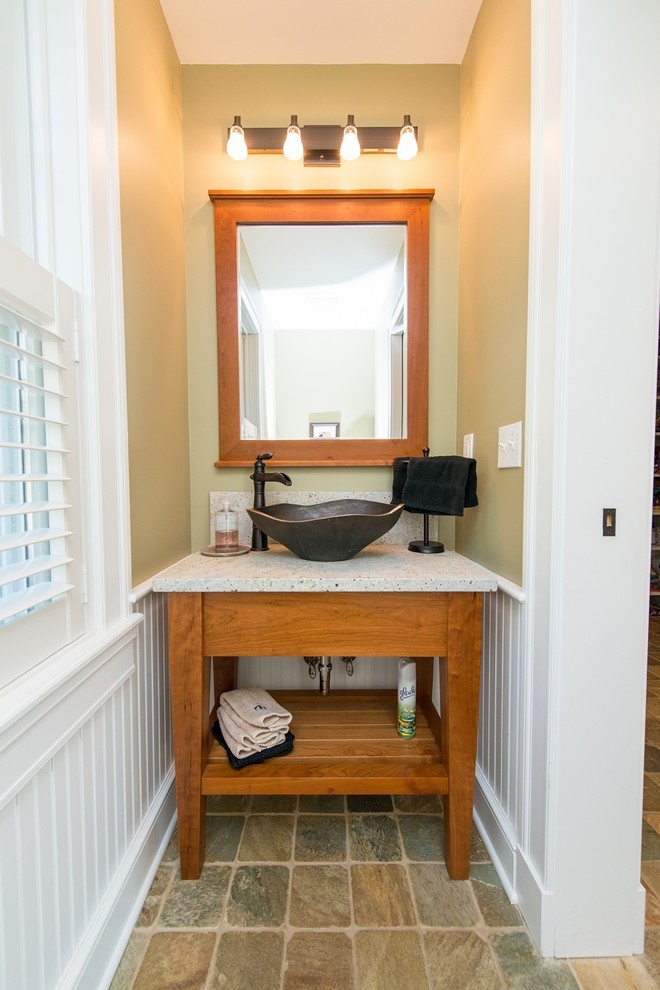 This is an example of a small traditional powder room in New York with a vessel sink, open cabinets, medium wood cabinets, a one-piece toilet, beige walls, porcelain floors and grey benchtops.