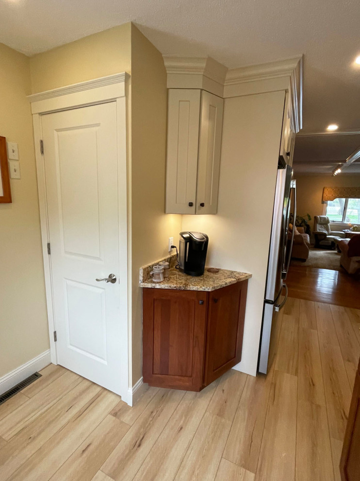 Eat-in kitchen - mid-sized transitional l-shaped light wood floor and brown floor eat-in kitchen idea in Boston with shaker cabinets, white cabinets, granite countertops, white backsplash, brown countertops, an undermount sink, stainless steel appliances, no island and stone tile backsplash