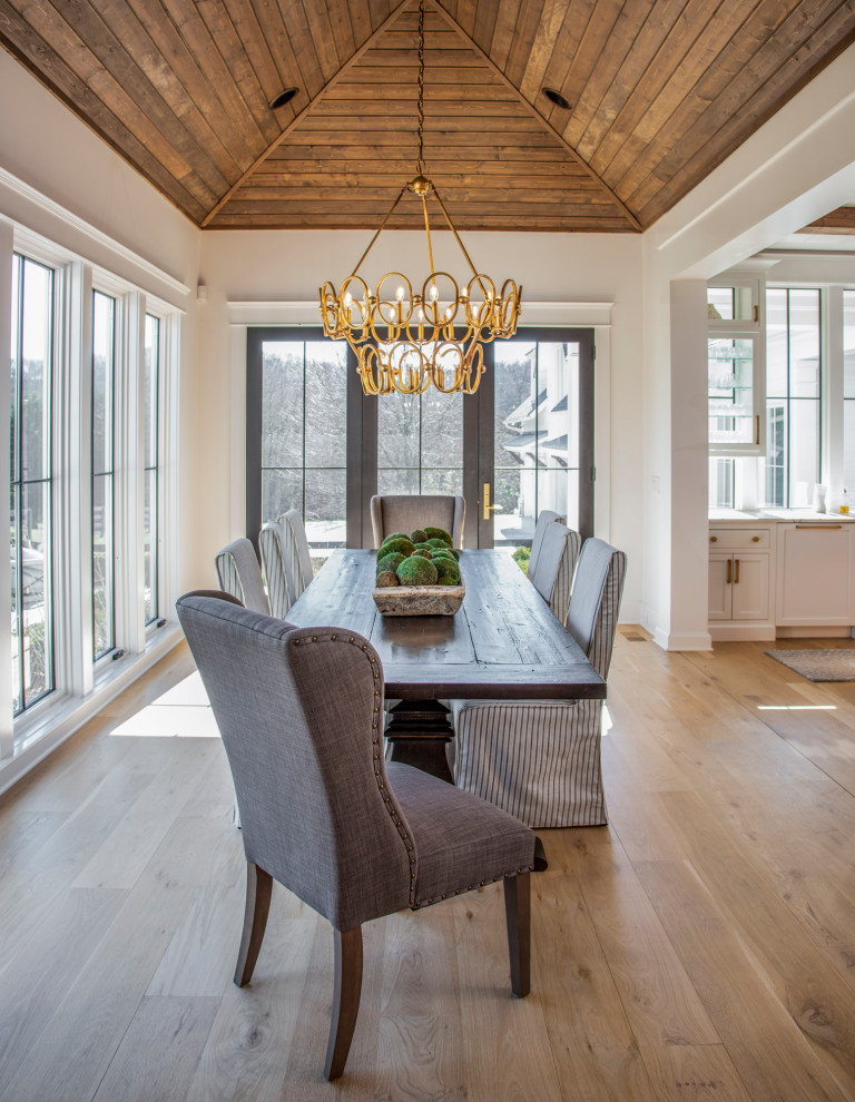 Modelo de comedor de estilo de casa de campo grande abierto con suelo de madera clara, suelo marrón y vigas vistas