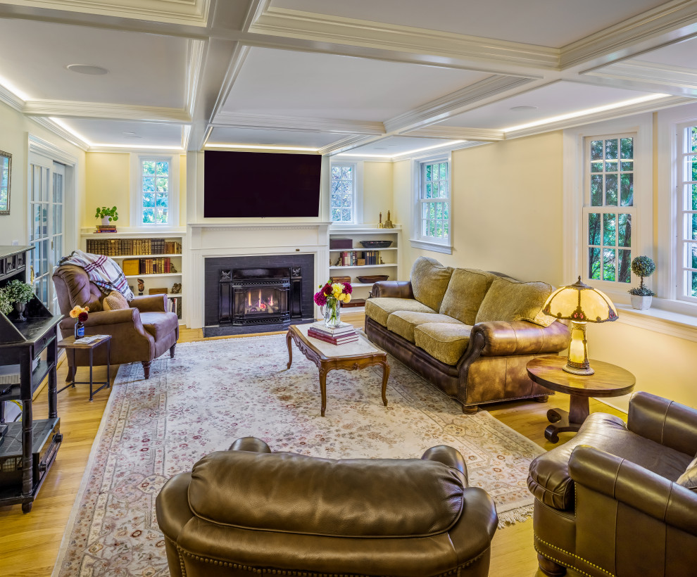 Photo of a mid-sized traditional enclosed living room in Providence with beige walls, medium hardwood floors, a standard fireplace, a stone fireplace surround, a wall-mounted tv, brown floor and coffered.