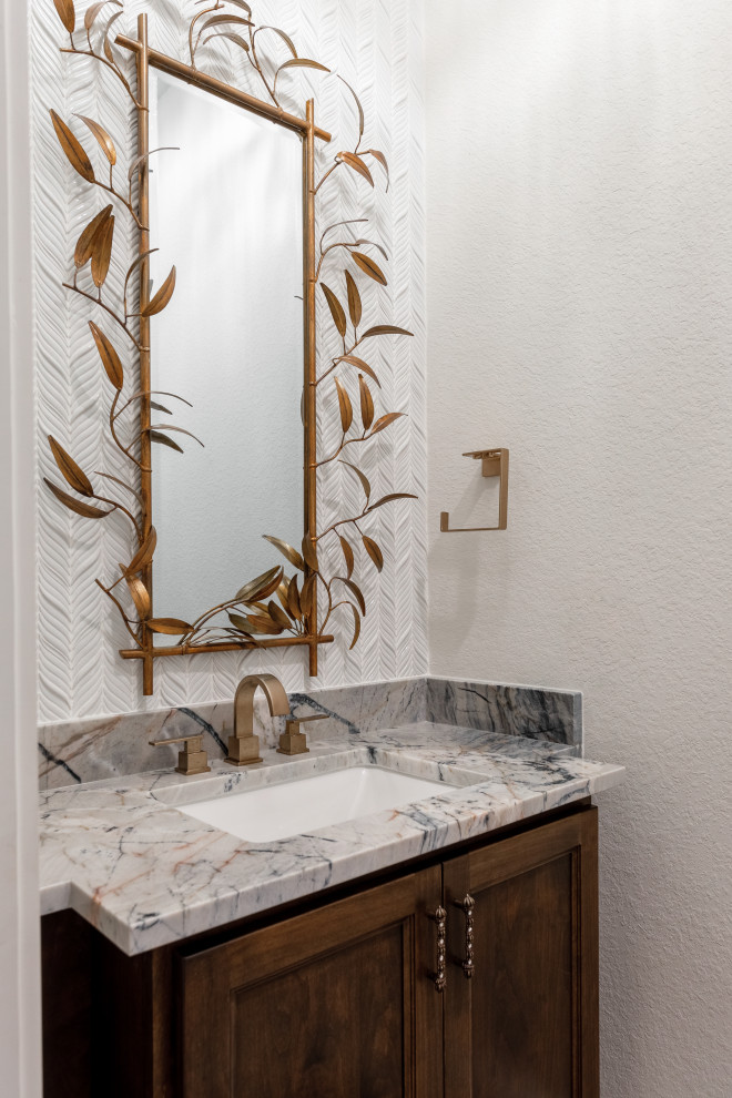 Powder room - mid-sized mediterranean white tile and ceramic tile porcelain tile and white floor powder room idea in Houston with shaker cabinets, medium tone wood cabinets, a one-piece toilet, white walls, a wall-mount sink, quartzite countertops, gray countertops and a built-in vanity