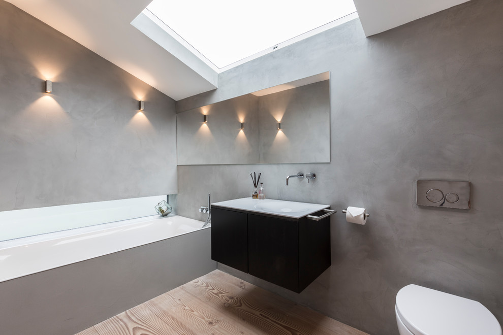 Mid-sized contemporary kids bathroom in London with an open shower, a one-piece toilet, grey walls, a drop-in sink, an open shower and flat-panel cabinets.
