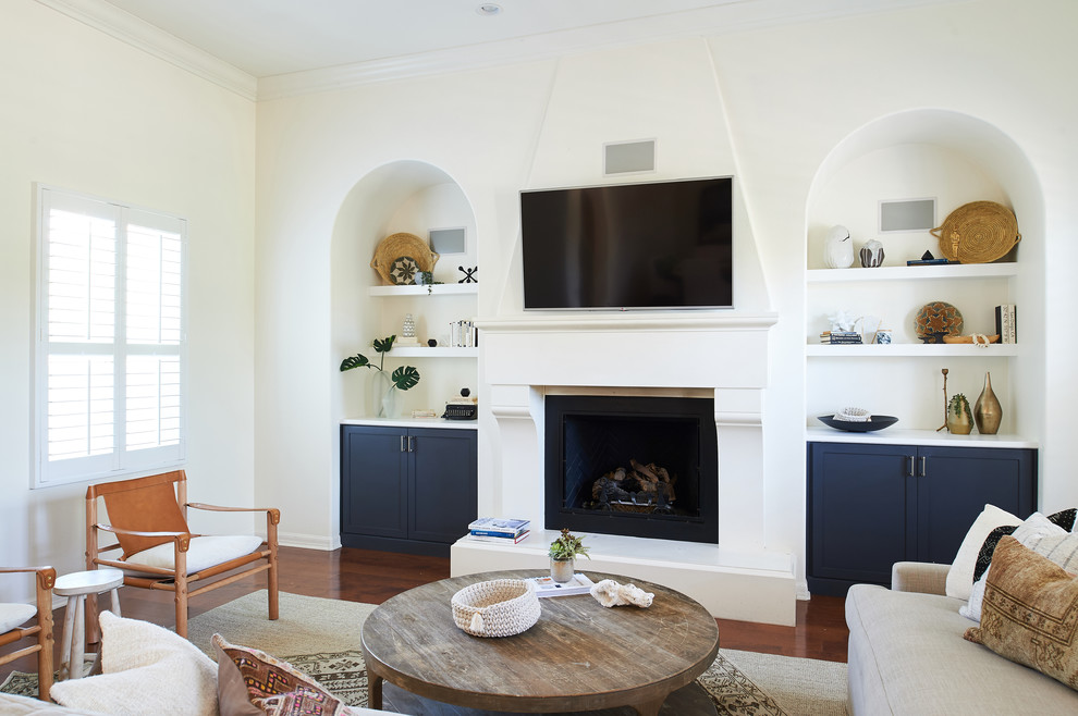 Inspiration for a beach style family room in San Diego with white walls, dark hardwood floors, a standard fireplace and a wall-mounted tv.