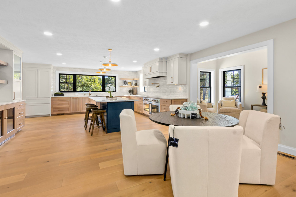 Inspiration for a mid-sized transitional u-shaped light wood floor open concept kitchen remodel with recessed-panel cabinets, white cabinets, quartzite countertops, stainless steel appliances and an island