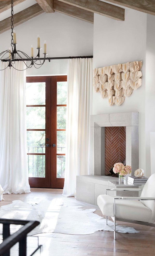Inspiration for a mediterranean bedroom in Austin with white walls, medium hardwood floors and a corner fireplace.