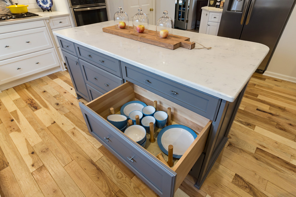 Inspiration for a large transitional u-shaped medium tone wood floor and brown floor enclosed kitchen remodel with an undermount sink, shaker cabinets, white cabinets, quartzite countertops, white backsplash, subway tile backsplash, stainless steel appliances and an island