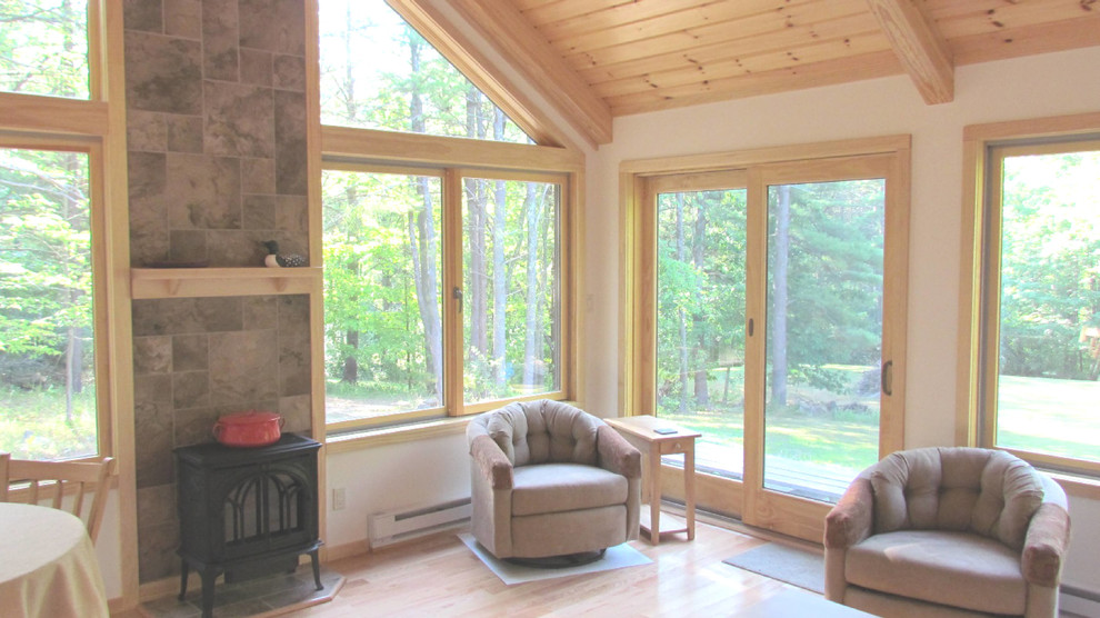 This is an example of a mid-sized traditional sunroom in Boston with light hardwood floors, a wood stove, a tile fireplace surround and a standard ceiling.