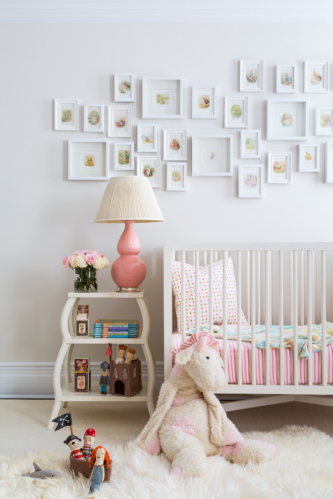 Photo of a large transitional nursery for girls in New York with pink walls and beige floor.