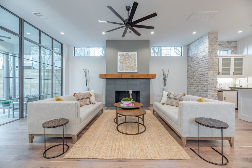 Photo of a large contemporary living room in Houston with a home bar, white walls, light hardwood floors, a standard fireplace and a stone fireplace surround.