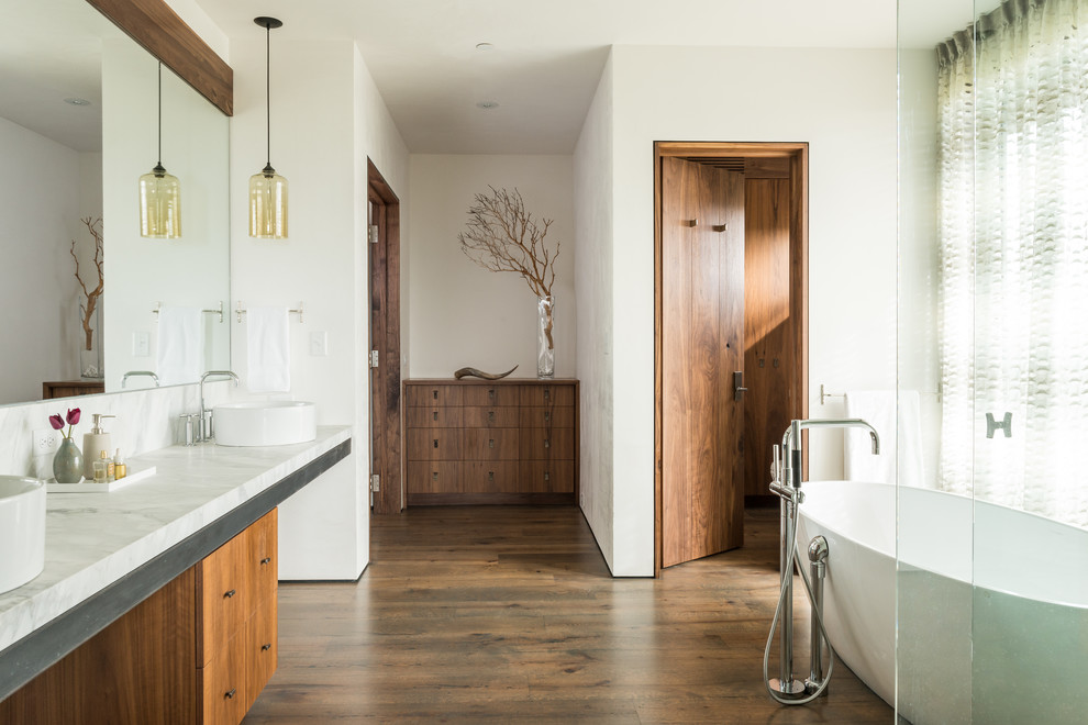 Country master bathroom in Other with flat-panel cabinets, medium wood cabinets, a freestanding tub, a curbless shower, white walls, medium hardwood floors and a vessel sink.