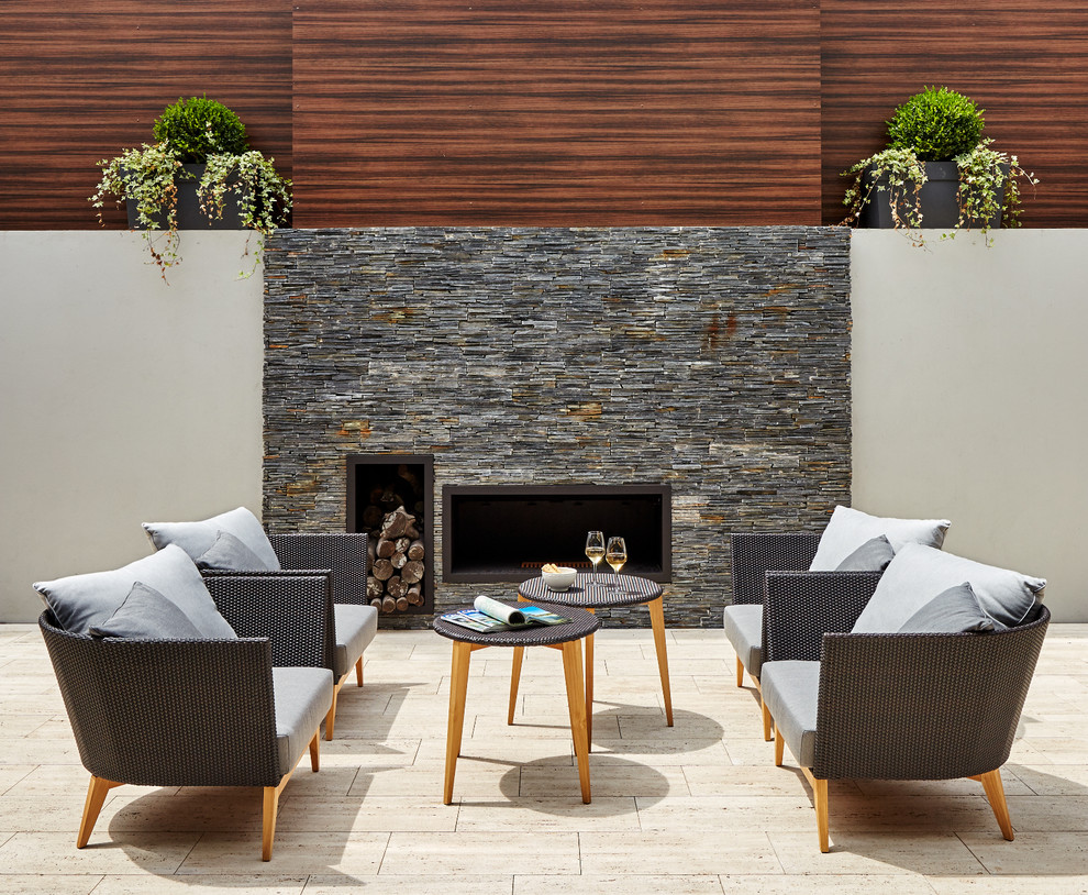 This is an example of a mid-sized contemporary courtyard patio in Other with no cover, natural stone pavers and a fire feature.