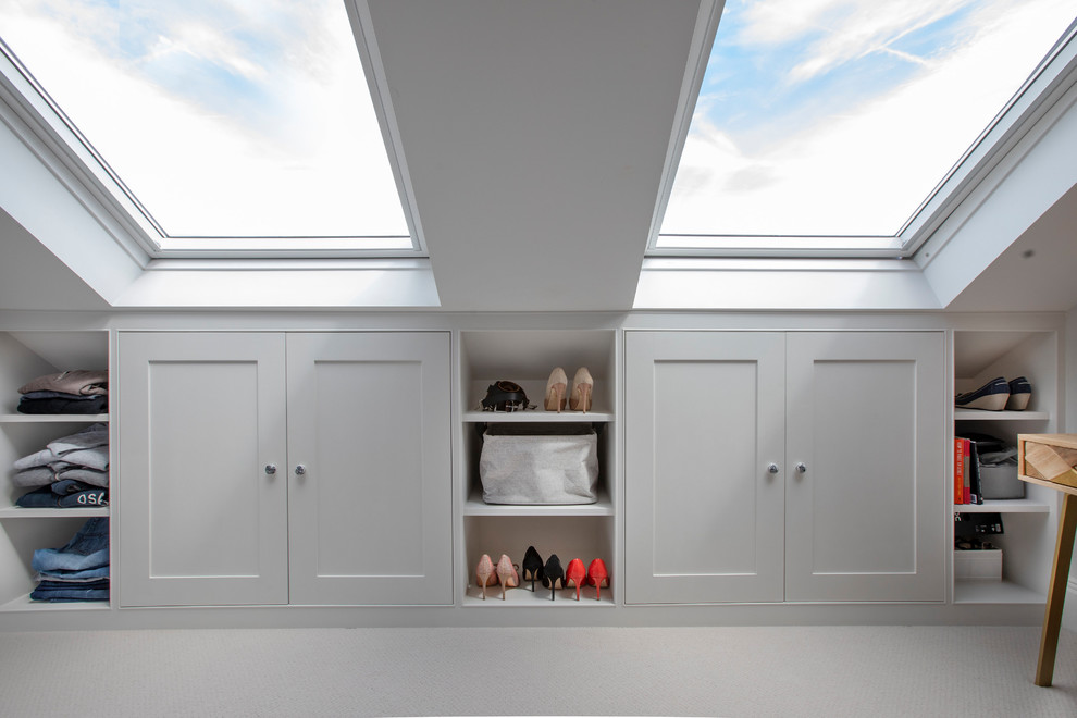 Inspiration for a transitional gender-neutral dressing room in London with shaker cabinets, white cabinets, carpet and white floor.