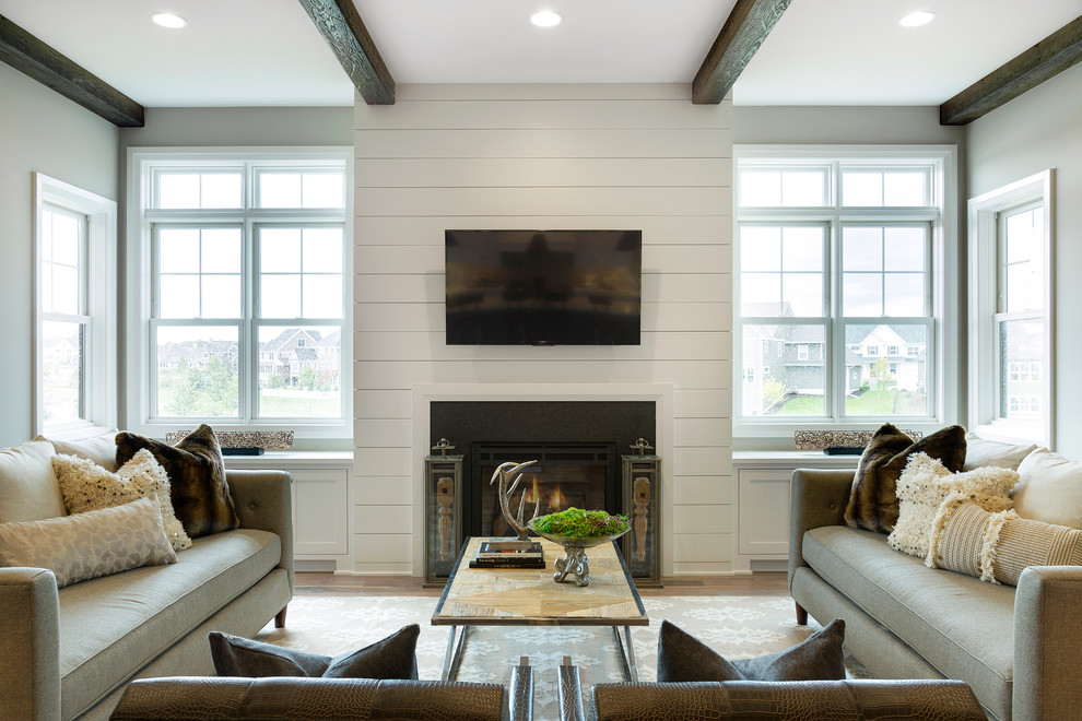 This is an example of a large transitional open concept living room in Minneapolis with grey walls, medium hardwood floors, a standard fireplace, a tile fireplace surround and a wall-mounted tv.