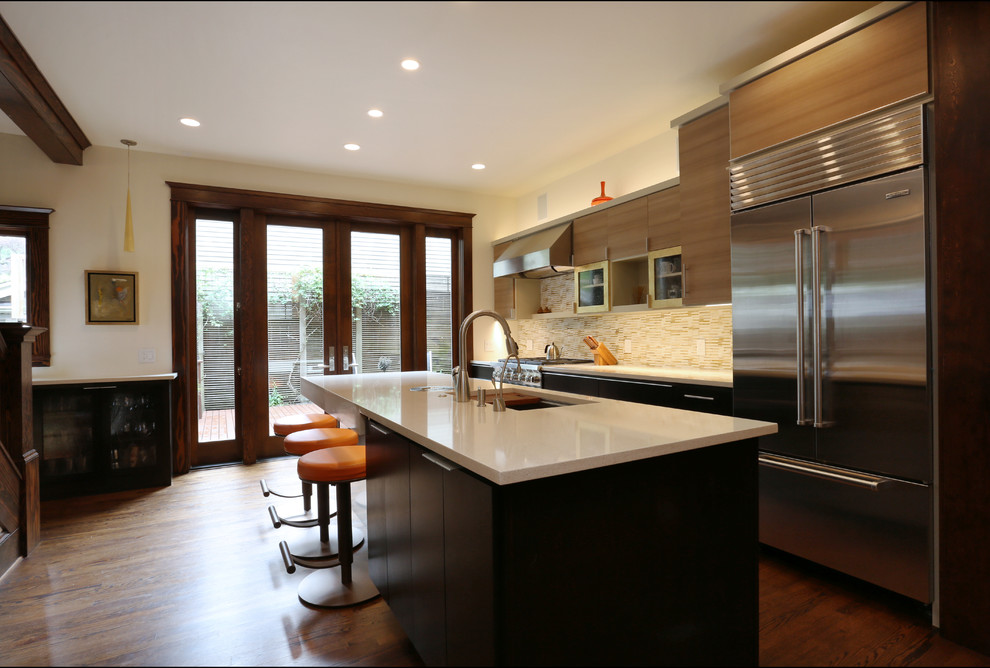 Foto på ett stort eklektiskt kök, med en undermonterad diskho, släta luckor, skåp i ljust trä, bänkskiva i kvarts, gult stänkskydd, stänkskydd i glaskakel, rostfria vitvaror, mörkt trägolv och en köksö